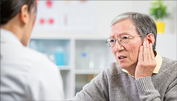 Older man holding his ear